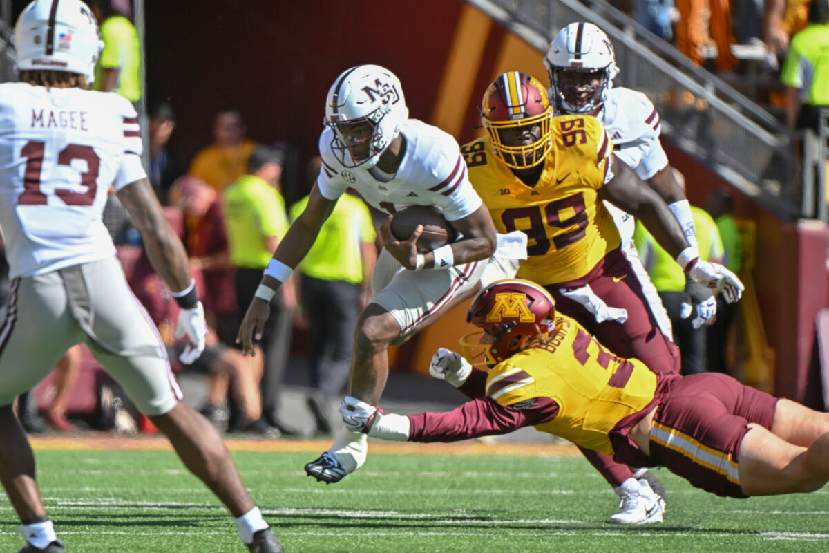 Mississippi State quarterback Kamario Taylor, center, leaps over Minnesota defensive lineman TJ Bush Jr. (3) in the first half during an NCAA college football game in Minneapolis, Saturday, Sept. 12, 2026. Credit: AP Photo/Craig Lassig